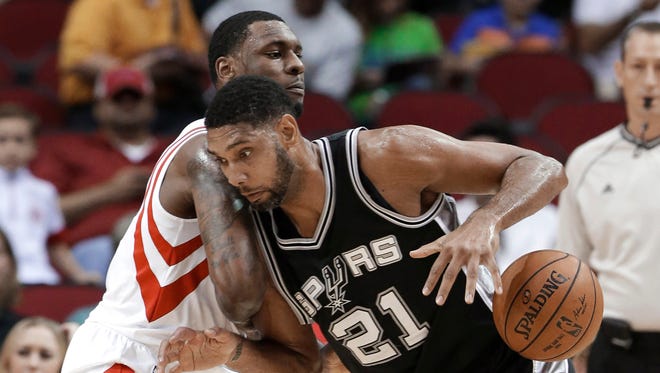 San Antonio Spurs' Tim Duncan (21) pushes against Houston Rockets' Terrence Jones during the first half of an NBA exhibition basketball game Friday, Oct. 24, 2014, in Houston.