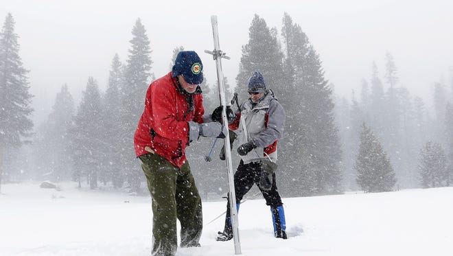 Frank Gehrke, chief of California Cooperative Snow Surveys Program for the Department of Water Resources, left,   pulls the snow depth survey pole from the snow pack as he conducts the first snow survey of the season at Echo Summit, Calif., Tuesday, Dec. 30,  2014. The survey showed the snow pack to to be 21.3  inches deep with a water content of 4.8 inches, which is  33 percent of normal for this site at this time of year.  At right is Dave Schmalenberger, of the Eat Bay Municipal Utility District, who accompanied Gehrke on the survey. (AP Photo/Rich Pedroncelli)