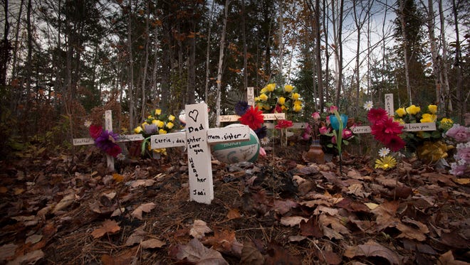 A small memorial stands in honor of the victims of the triple homicide of Jody Hutchinson, 42, and sisters Carrie Nelson, 31, and Heather Aldrich, 25 on River Road in Doyle Twp, Tuesday, October 20, 2015.