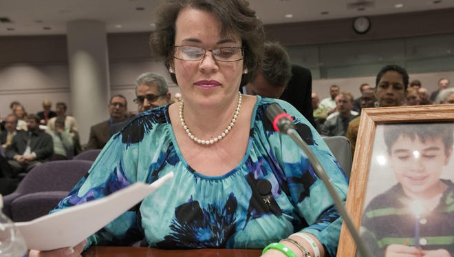 In this Jan. 28, 2013, file photo, Veronique Pozner places her hand next to artwork made by her son Noah before testifying before a hearing of a legislative subcommittee reviewing gun laws at the Legislative Office Building in Hartford, Conn.
