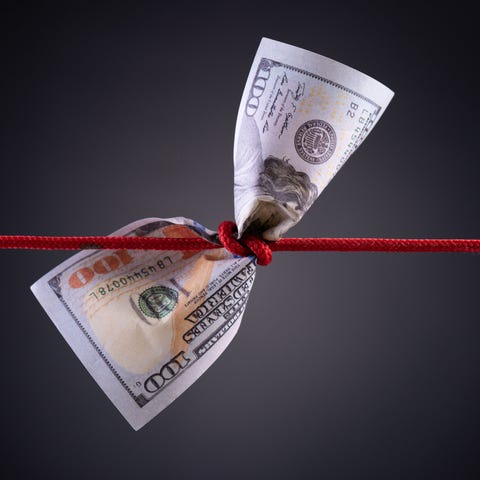 A red string knotted around a hundred-dollar bill.