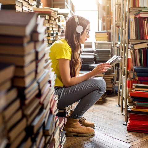 A young woman listens to music in a library.