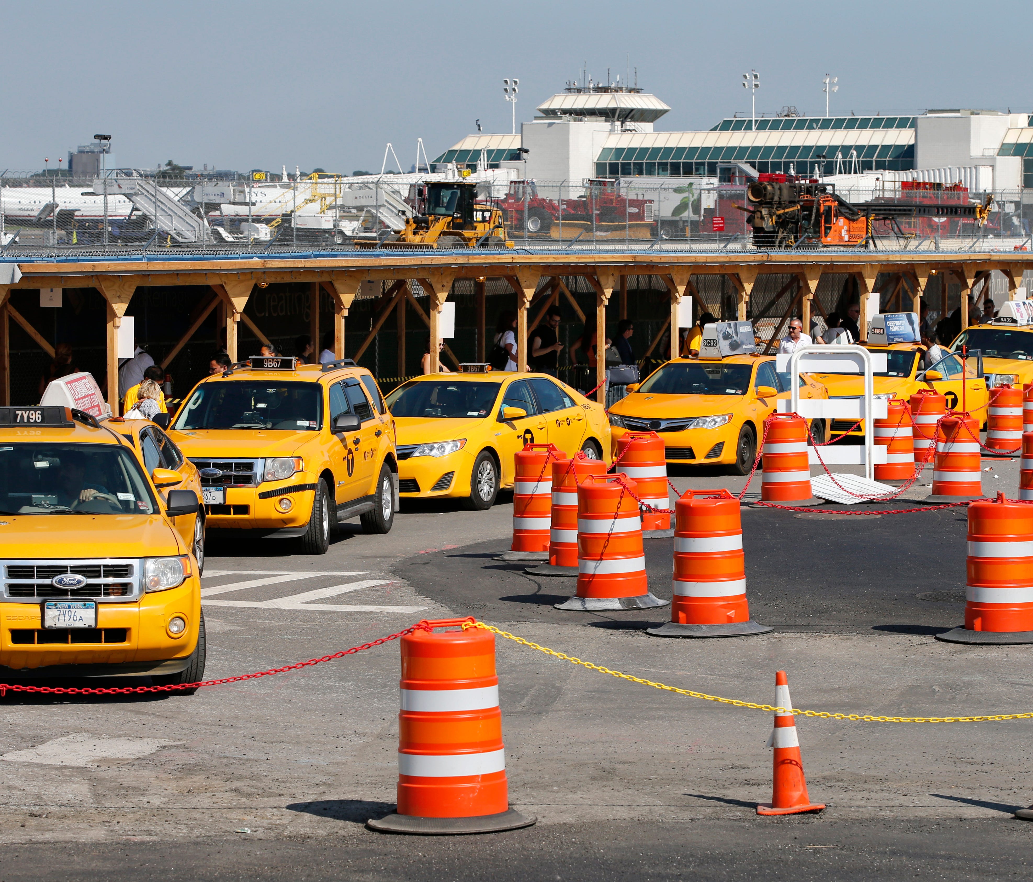 In this Aug. 24, 2016, photo, taxis line up to pick up arriving passengers near Terminal B at LaGuardia Airport in New York, where a $4 billion renovation is underway.