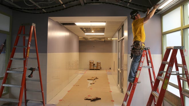 Browen Timothy installs ceiling panels on the second floor of School 12.  The school is scheduled to reopen next fall. 