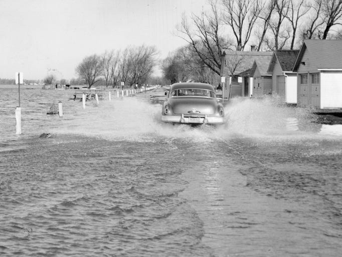 A car splashes through several inches of water on Edgemere