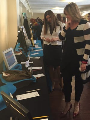 Michelle Holliday, left, and Kate Hogg, right, browse the artwork up for bid during the 2015 Women's Fund luncheon.