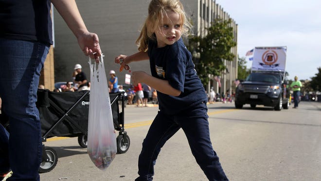 Claire Van Schyndel, 5, prepares to throw a handful of candy to the crowd Sept. 5 next to her mother, Jenny Van Schyndel, at the Neenah-Menasha Labor Day Parade in Menasha.