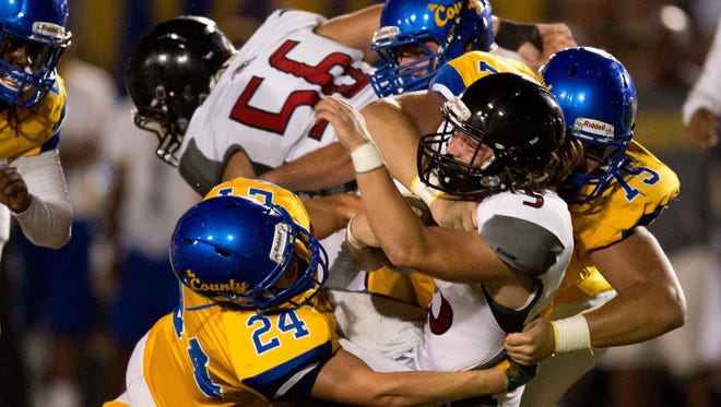 South Fork quarterback Stone Labanowitz is sacked in the first quarter by Martin County's Jayce Golden (left) and Matt Vanderbilt (right) during the Martin Bowl high school football rivalry game Friday, Sept. 30, 2016, at Martin County High School in Stuart.
