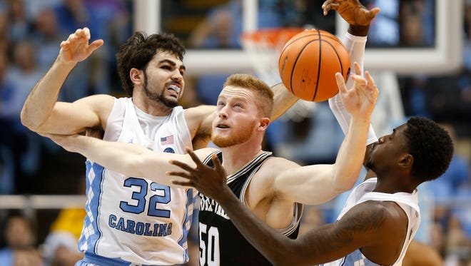 North Carolina forward Luke Maye (32) and teammate North Carolina guard Jalek Felton (5) battle Wofford center Matthew Pegram for a loose ball during the first half of an NCAA college basketball game in Chapel Hill, N.C., Wednesday, Dec. 20, 2017.