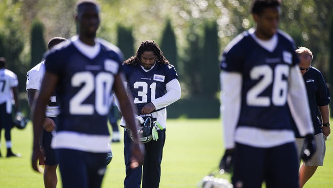 Seattle Seahawks running back Marshawn Lynch walks off the field, wearing teammate Kam Chancellor's jersey, after NFL football practice Thursday, Sept. 10, 2015, in Renton, Wash. Chancellor is in a contract dispute with the team and did not report when his teammates gathered for training camp.