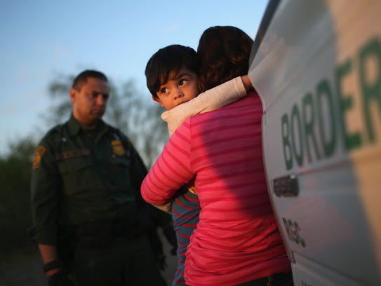 A 1-year-old from El Salvador clings to his mother
