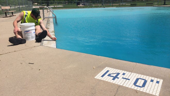 Jon Clancy, a building maintenance assistant for the City of De Pere, removes leaves and other debris from the water at the newly filled Legion Park pool. De Pere's two pools at Legion and VFW parks open for the season June 11.
