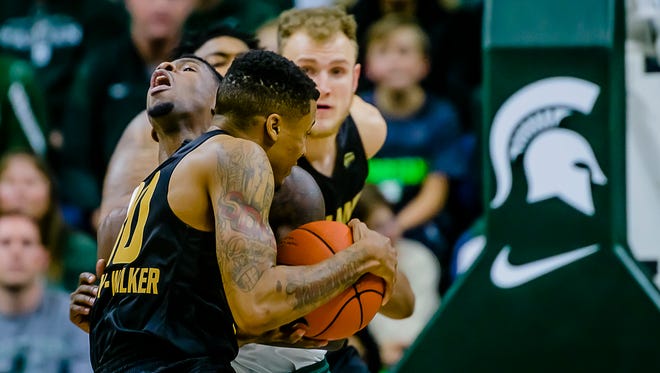 Eron Harris ,background, of MSU takes a charge by Sherron Dorsey-Walker of Oakland during their game in East Lansing.