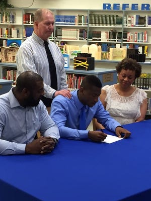 Ernest Shockley (center) signs his letter of intent to play football at Division II Bowie State. He is surrounded by his parents and Stephen Decatur head football coach, Bob Knox.
