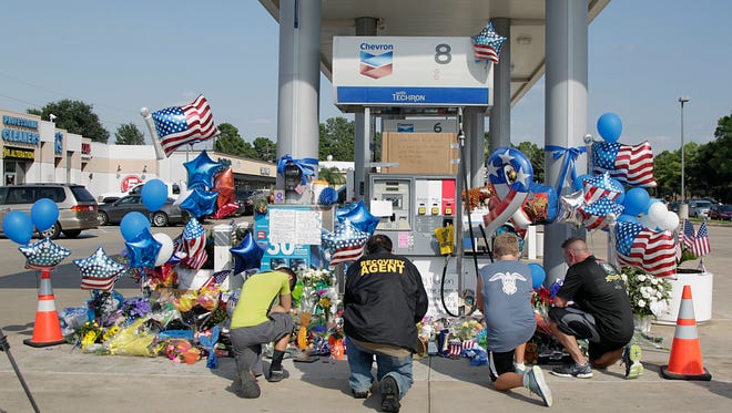 Mourners gather at a gas station in Houston on Aug. 29, 2015, to pay their respects at a makeshift memorial for Harris County Sheriff's Deputy Darren Goforth, who was shot and killed while filling his patrol car.