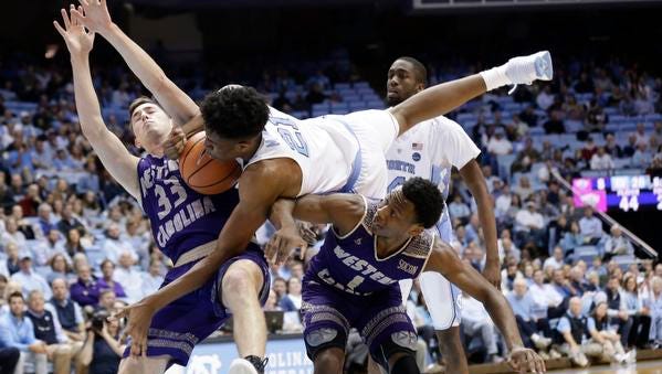 North Carolina's Sterling Manley (21) falls over Western Carolina's Onno Steger (33) and Desmond Johnson (1) during the first half of an NCAA college basketball game in Chapel Hill, N.C., Wednesday, Dec. 6, 2017. (AP Photo/Gerry Broome)