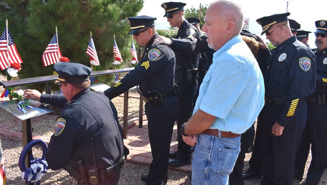 Alamogordo Police Chief Daron Syling kneels at fallen officer Clint Corvinus's plaque inside the Law Enforcement Officers Memorial Garden on Saturday, Sept. 2. Alongside Syling are the officers of the Alamogordo Police Department and Corvinus's parents.