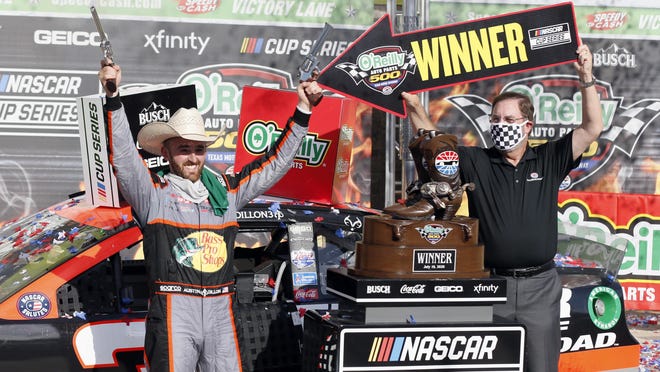 Texas Motor Speedway President Eddie Gossage holds a "winner" sign as Austin Dillon celebrates with the tradtional six-shooters Sunday in Fort Worth.