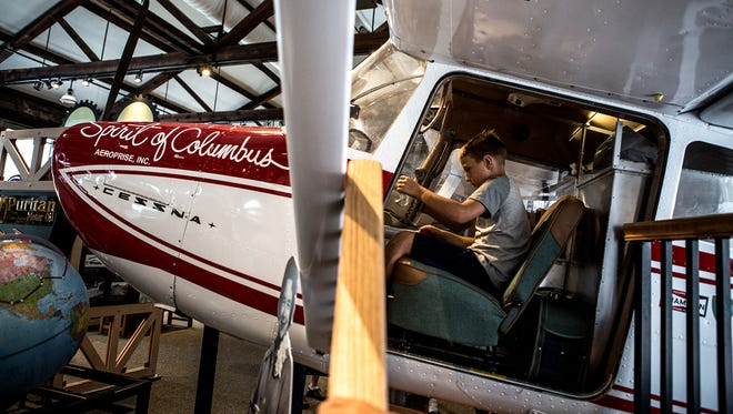 Dylan Hunter sits in a replica of the Spirit of Columbus, the airplane Jerrie Mock flew solo around the world. The Works celebrated their 20th anniversary Saturday with a dedication of of a Jerrie Mock exhibit.