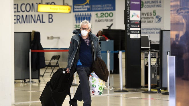 Passengers arriving at Newark Liberty International Airport take precautions against the coronavirus COVID-19 on Thursday, March 12, 2020, ahead of a 30-day travel ban from Europe, imposed by President Trump, that goes into effect on Friday.