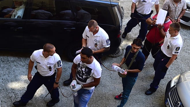 Four suspects are led by Hungarian police officials at Kecskemet court. Four suspects in the deaths of 71 migrants found in an abandoned truck in Austria arrived Saturday for a court hearing in Hungary.