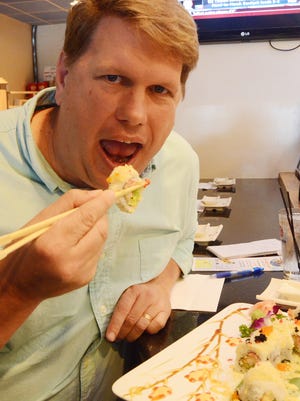 Bill Broderick taking a bite of a Battle Creek roll at Sakura Sushi Bar and Grill on Beckley Road.