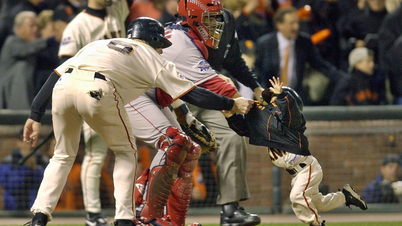 FILE - In this Oct. 24, 2002, file photo, San Francisco Giants' J.T. Snow, left, drags 3-year-old Darren Baker, son of then-Giants manager Dusty Baker, away from home plate and the path of oncoming baserunner David Bell after scoring in the seventh inning of World Series Game 5 in San Francisco.
