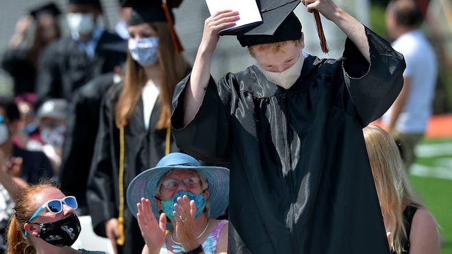 Wayland High School graduate Aidan Keenan moves his tassel from the right side to the left at the completion of commencement exercises at the school's new football stadium Saturday morning. Graduates were seated in "pods" with their immediate family members.