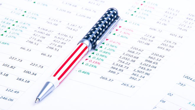 An American flag-themed pen lying atop a printout of financial data.