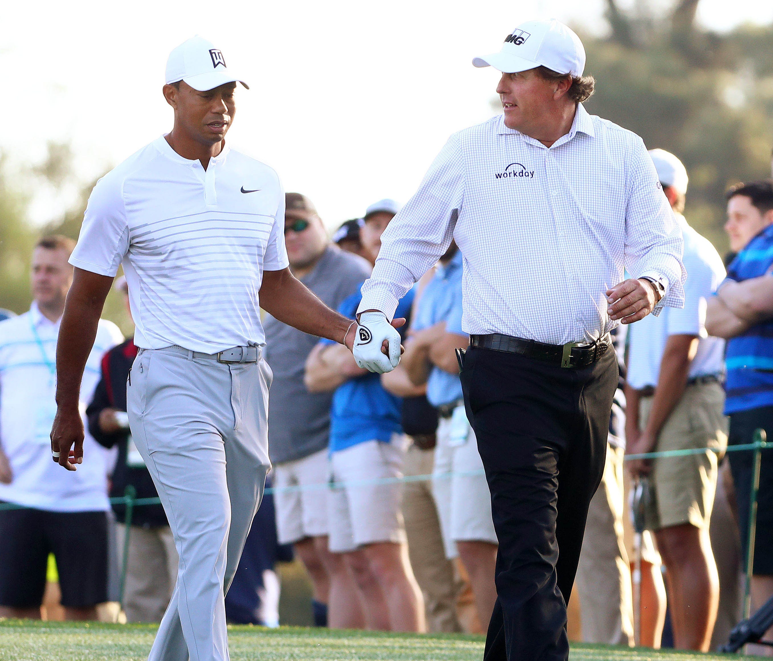 Tiger Woods and Phil Mickelson walk off the 10th tee box hand-in-hand during their practice round on the back nine at Augusta National in preparation for The Masters.
