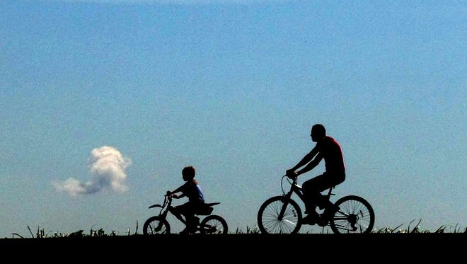 A man and his grandson ride their bikes on a trail near Lunken Airport in the East End.