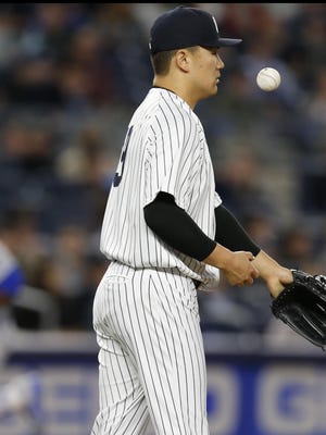 New York Yankees starting pitcher Masahiro Tanaka (19) tosses a ball up after allowing a fifth-inning, three-run, home run to Kansas City Royals' Lorenzo Cain.