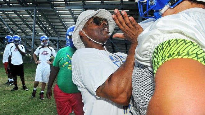 Titusville High's Head Coach Wayne Lawrence works with his offensive line players as they run through some drills during Tuesday afternoon practice held at Titusville High School as they get ready for the upcoming season.