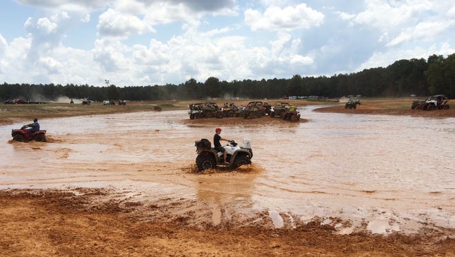 ATV drivers test their vehicles' abilities in a muddy pond at Muddy Bottoms ATV park.