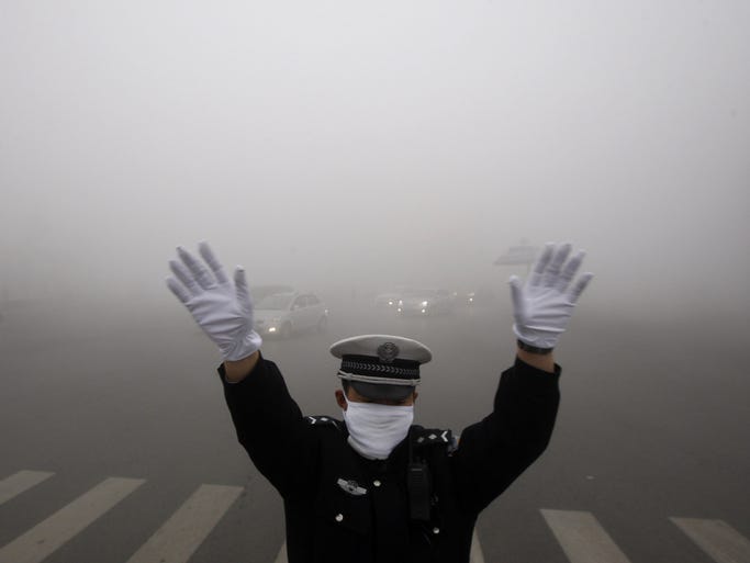 A policeman gestures as he works on a street in heavy smog in Harbin, northeast China's Heilongjiang province, on Oct. 21.