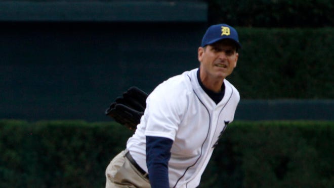 Michigan coach Jim Harbaugh follows through on his pitch to Tigers manager Brad Ausmus as Harbaugh threw out the first pitch before the game between the Detroit Tigers and the Pittsburgh Pirates on June 30, 2015.