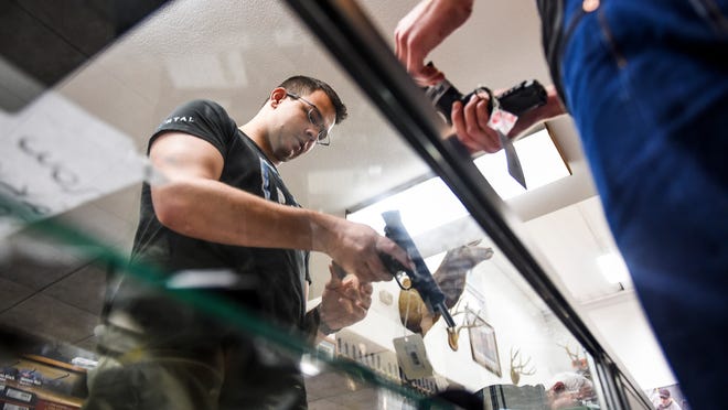 Jeremy Adams looks at guns with the help of employee Anthony Steffanic at Rocky Mountain Shooters Supply in this file photo from March. Despite gun-control legislation, gun purchases have remained brisk.