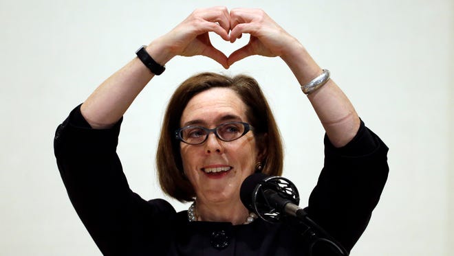 Oregon Gov. Kate Brown forms a heart with her hands as she says "I love Oregon" during her State of the State address in Portland, Ore., Friday, April 17, 2015. (AP Photo/Don Ryan)