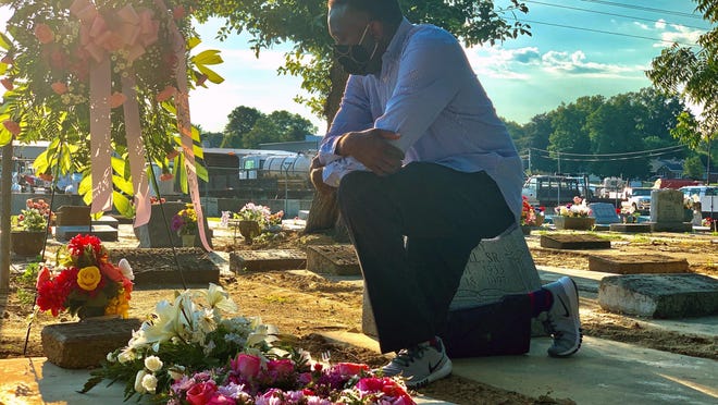 Will Boyd kneels at the grave of a family member who died after contracting the coronavirus, Saturday, June 20, 2020, in Montgomery, Ala. He says his family has lost multiple family members to COVID-19. (AP Photo/Kim Chandler)