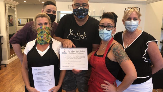 Employees of Palm Beach Beauty Salon in Palm Beach Gardens display their certificate of verification for compliance with Phase I of Gov. DeSantis' Executive Order.