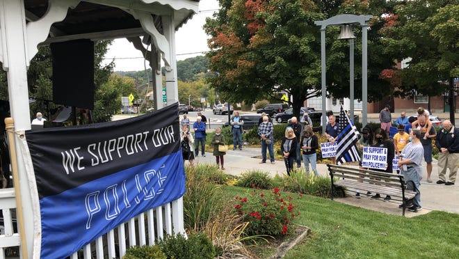 Local residents hold signs and wave flags as they listen to speakers during a rally in support of police officers on the Newton Green Saturday, Sept. 26.