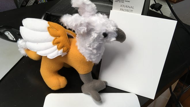 The Amesbury Public Library is taking its Summer Reading program online this year. Shown here is Augustus the Griffin with one of the journals the library be giving away.