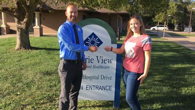 Patrick Flaming, RN, BSN, director of access services at Prairie View, accepts $472 from Breanna Schnelle, McPherson Hi-Steppers captain and organizer of the suicide prevention awareness campaign and fundraiser.