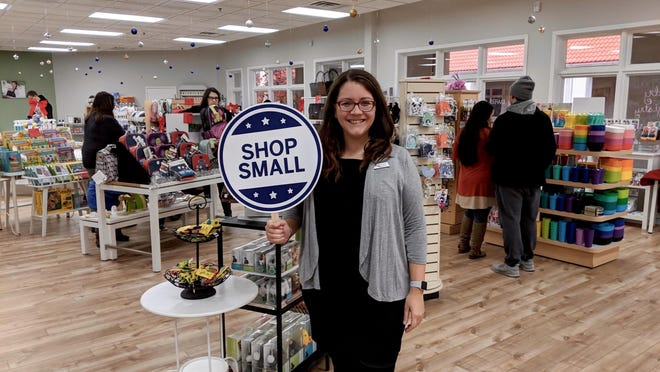 Marissa Berghorst, co-owner of EcoBuns in Holland Town Center, poses for a photo with a "Shop Small" sign on Small Business Saturday 2018. This year, Berghorst and other local business owners are encouraging visitors to start their holiday shopping early.