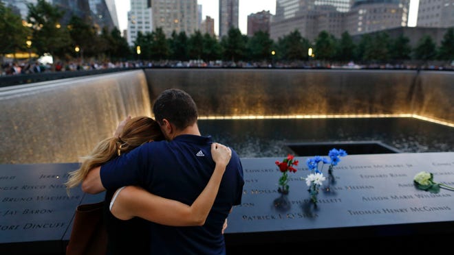 In this Sept. 11, 2014 file photo, David Pykon, right, and his fiancé Shelli Scrimale embrace while observing the 13th anniversary of the attacks on the World Trade Center at the north pool of the memorial in New York. (AP Photo/Julie Jacobson, File)