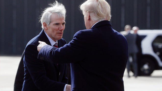 In this file photo, a wind-blown Ohio GOP Sen. Rob Portman welcomes President Donald Trump to Ohio.