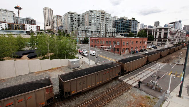 In this May 29, 2012, file photo, a train hauling coal to British Columbia heads north out of Seattle between office buildings, condos and the downtown waterfront. American Indian tribes and environmentalists in the Pacific Northwest have successfully fought a slew of fossil fuel export projects in recent years and pushed for local regulations to prevent new proposals.