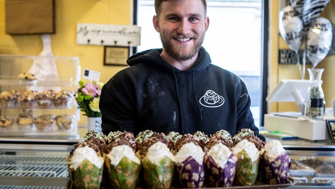 Aaron Pound holds a tray of cupcakes for sale in his bakery, Rolls by the Pound. Pound took over the lease and bought the recipes for all his baked good from McClain Creations.