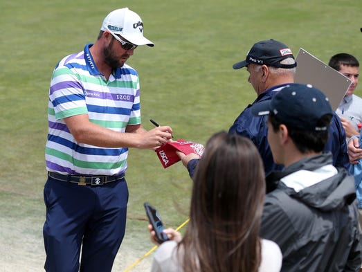 Marc Leishman signs autographs for fans as he walks