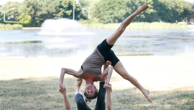 Yogis Eva Kane of Penfield as flyer and Leah Gerenski of Webster as base practice AcroYoga during a jam at Cobbs Hill Park. The event is free and led by instructor JoAnne Wu.